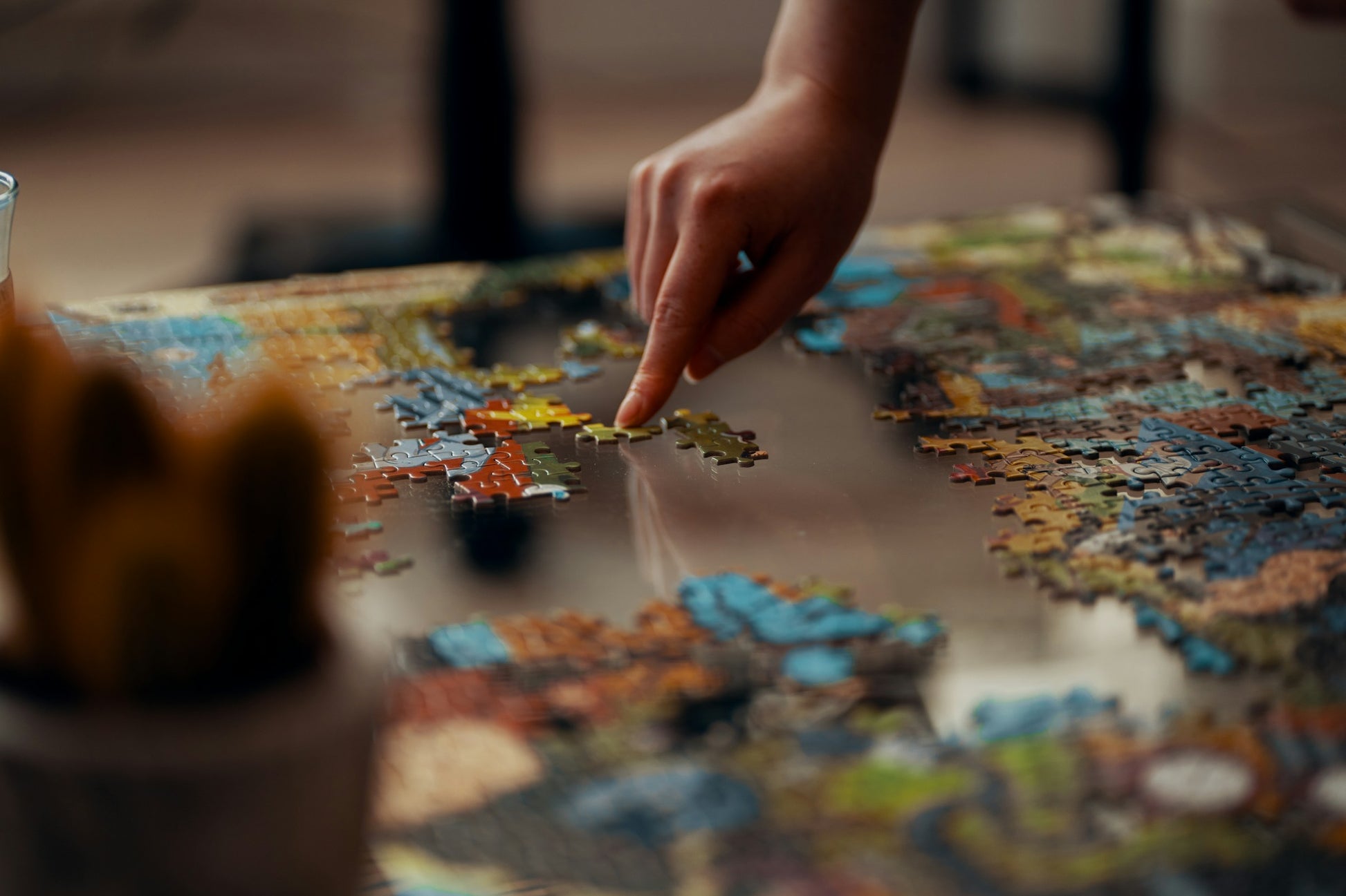 Person placing a jigsaw puzzle piece on a partially assembled puzzle [unsplash:sWlDOWk0Jp8]