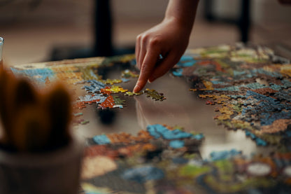 Person placing a jigsaw puzzle piece on a partially assembled puzzle [unsplash:sWlDOWk0Jp8]